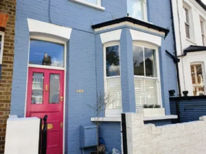 A blue brick period terraced house with a pink door in West London benefiting from planning permission for an extension in the back garden